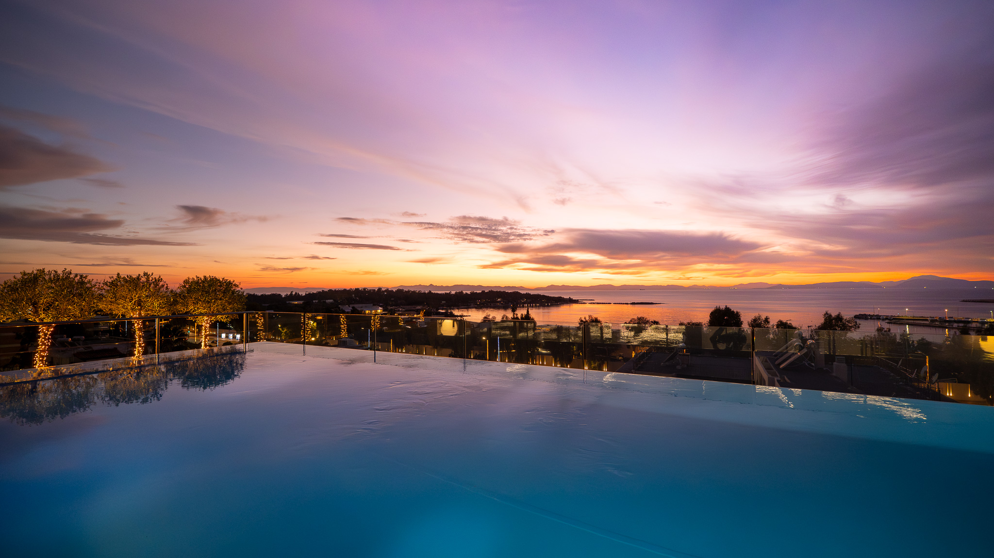 Dusit Suites Athens, deep twilight rooftop pool with lit coastline