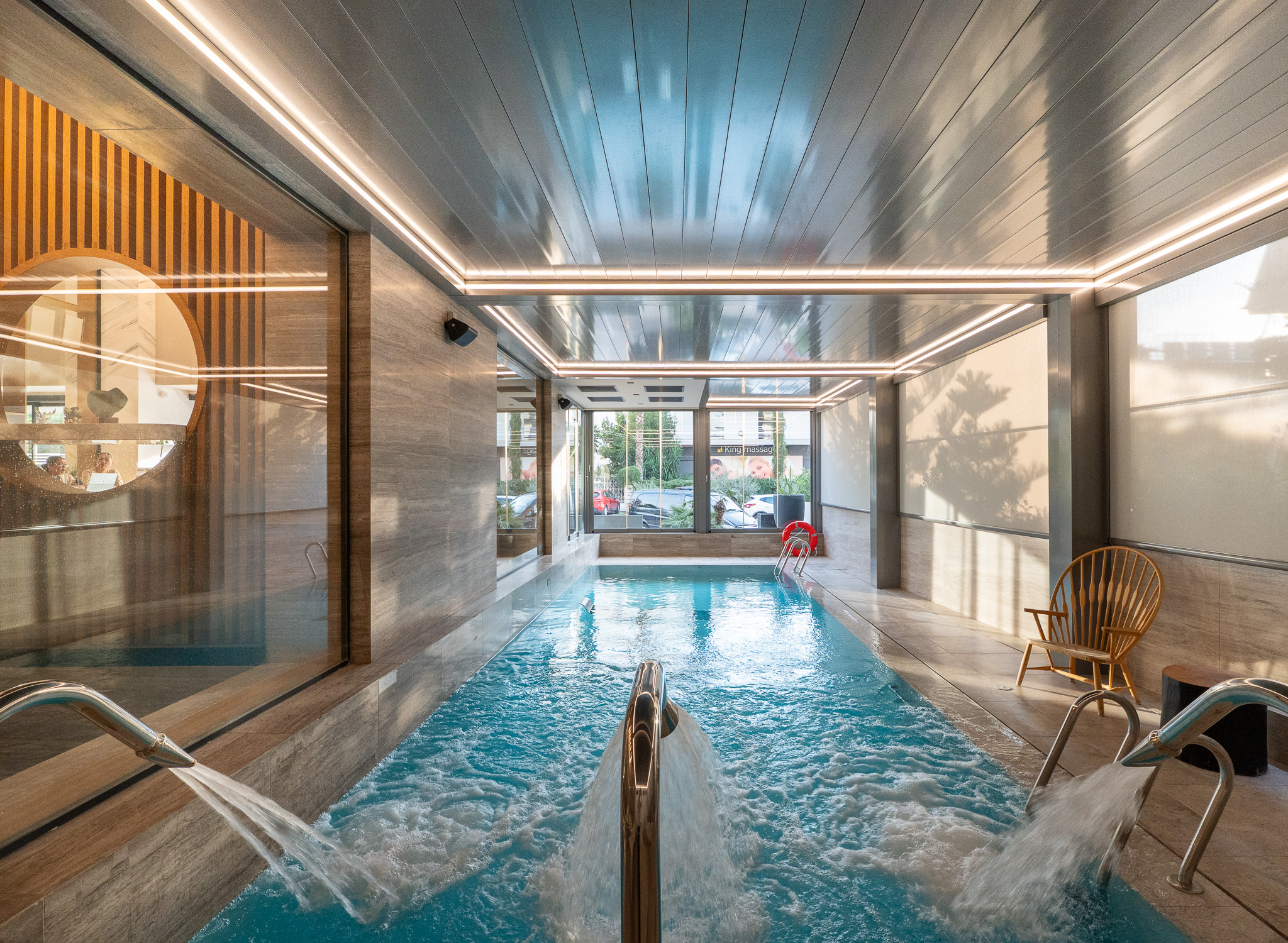 Dusit Suites Athens, indoor lap pool with travertine walls and ribbed-wood sauna